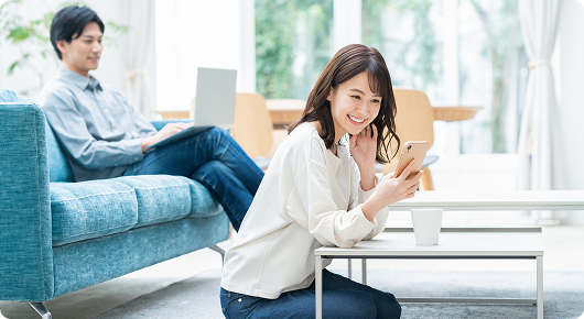自宅でくつろぎながら申込みをする女性